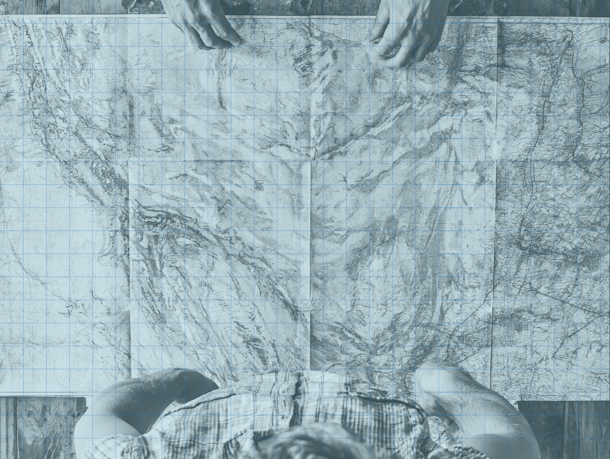 Several people's hands spreading out a large map pieced together from separate sheets
